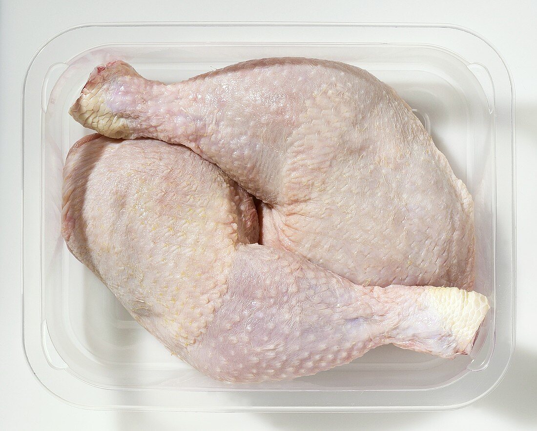 Two chicken legs in plastic container