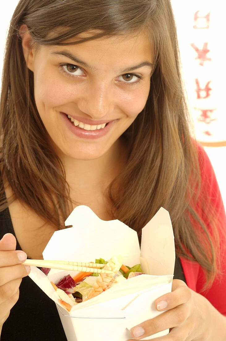 Frau isst asiatisches Gericht aus Take-Out-Box