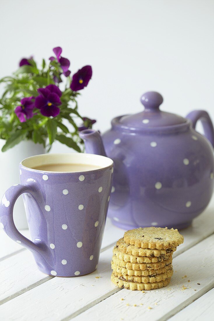 Teapot, mug of tea, fruit shortcakes and pansies