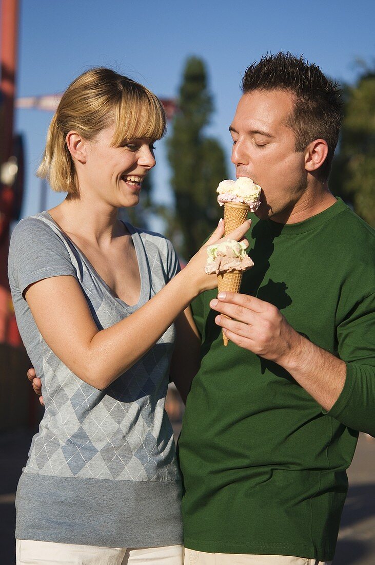 Fröhliches Paar mit Eistüten im Freien