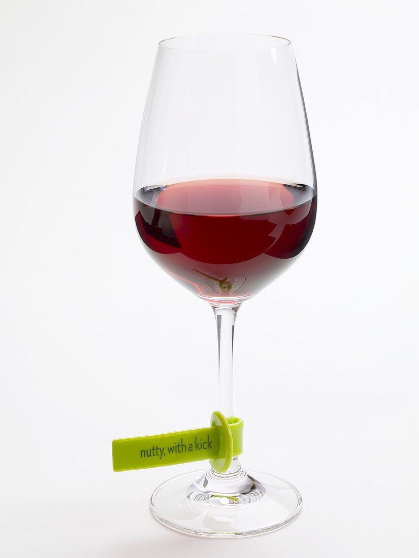 Glass of red wine with plastic label describing the wine