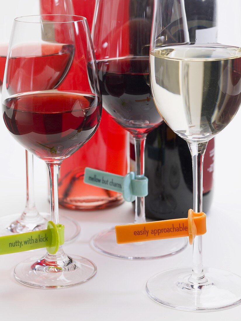 Glasses of wine with plastic labels describing the wine, bottles