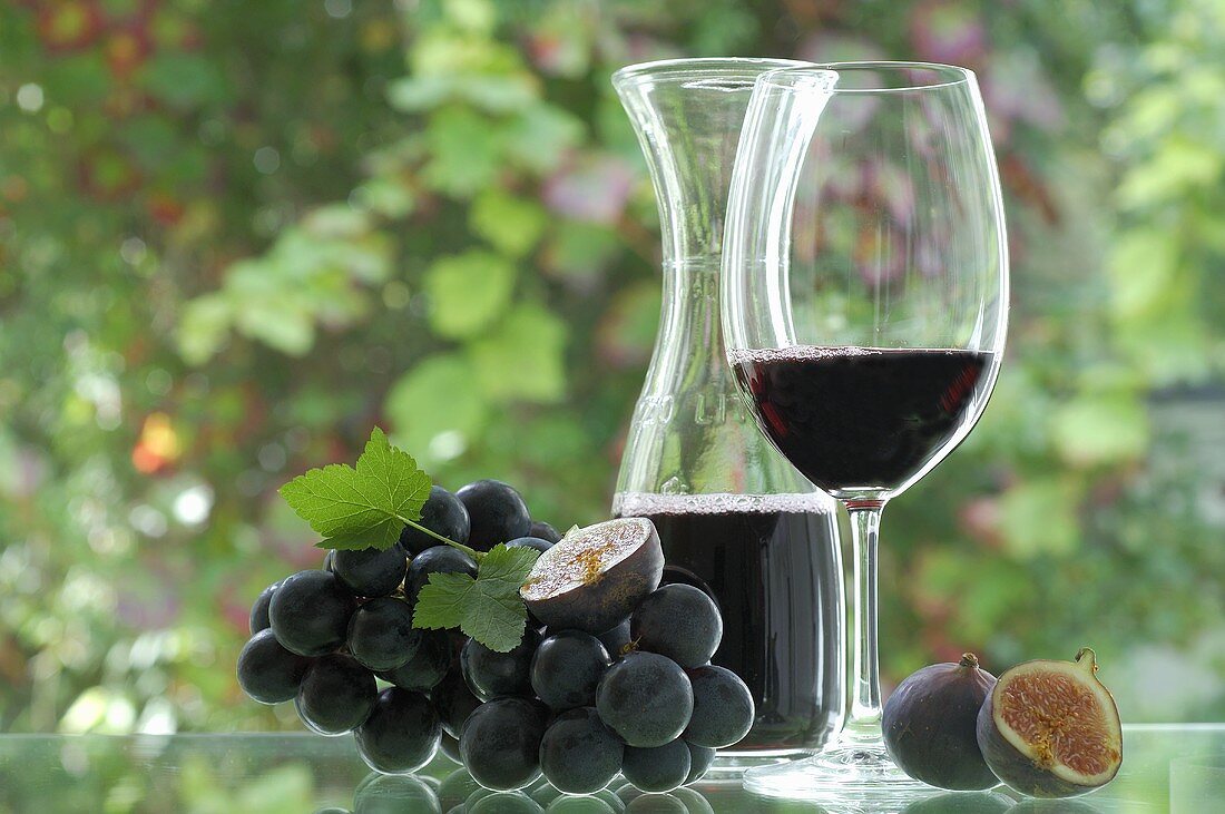Red wine in glass and carafe, black grapes, figs