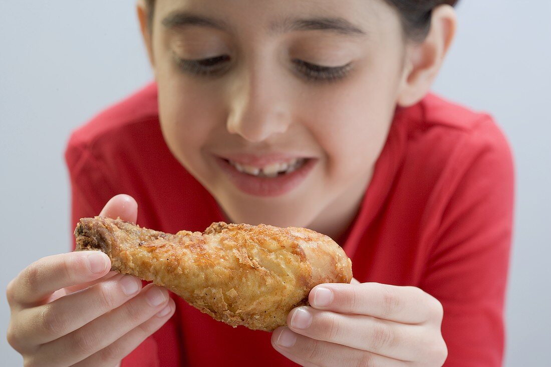 Kleines Mädchen blickt auf frittierte Hähnchenkeule