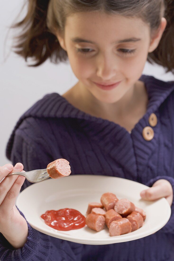 Kleines Mädchen isst Wiener Würstchen mit Ketchup