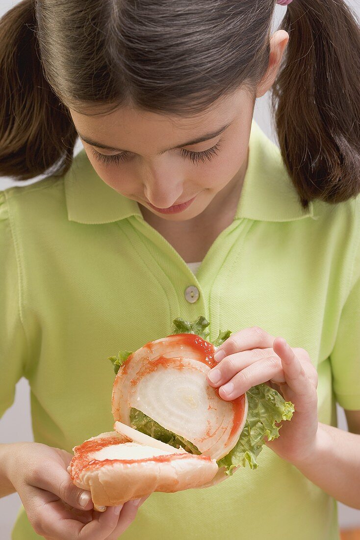 Kleines Mädchen blickt in aufgeklappten Burger