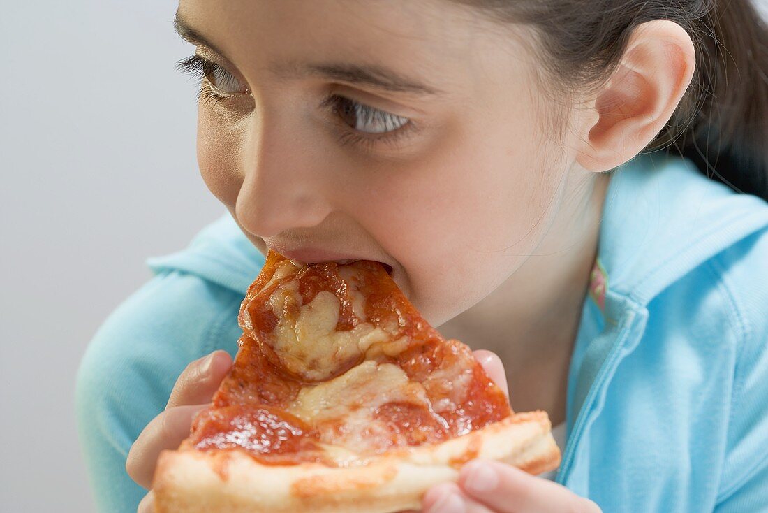 Kleines Mädchen isst Stück Pizza