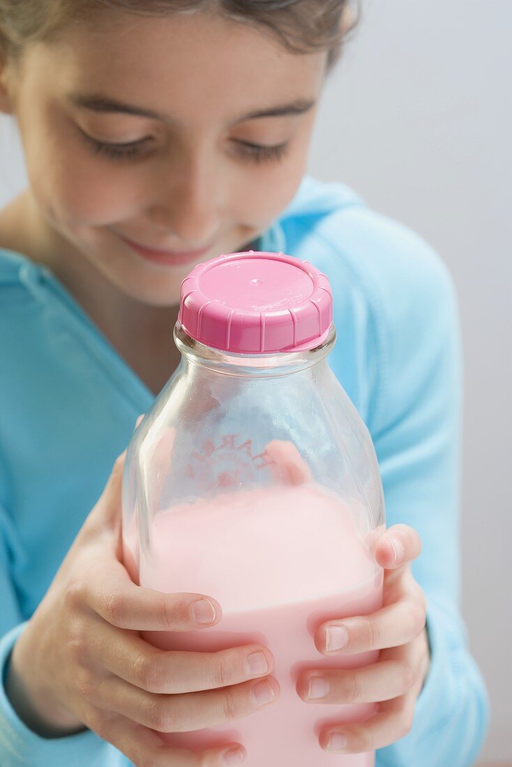 Kleines Mädchen hält Flasche Erdbeermilch