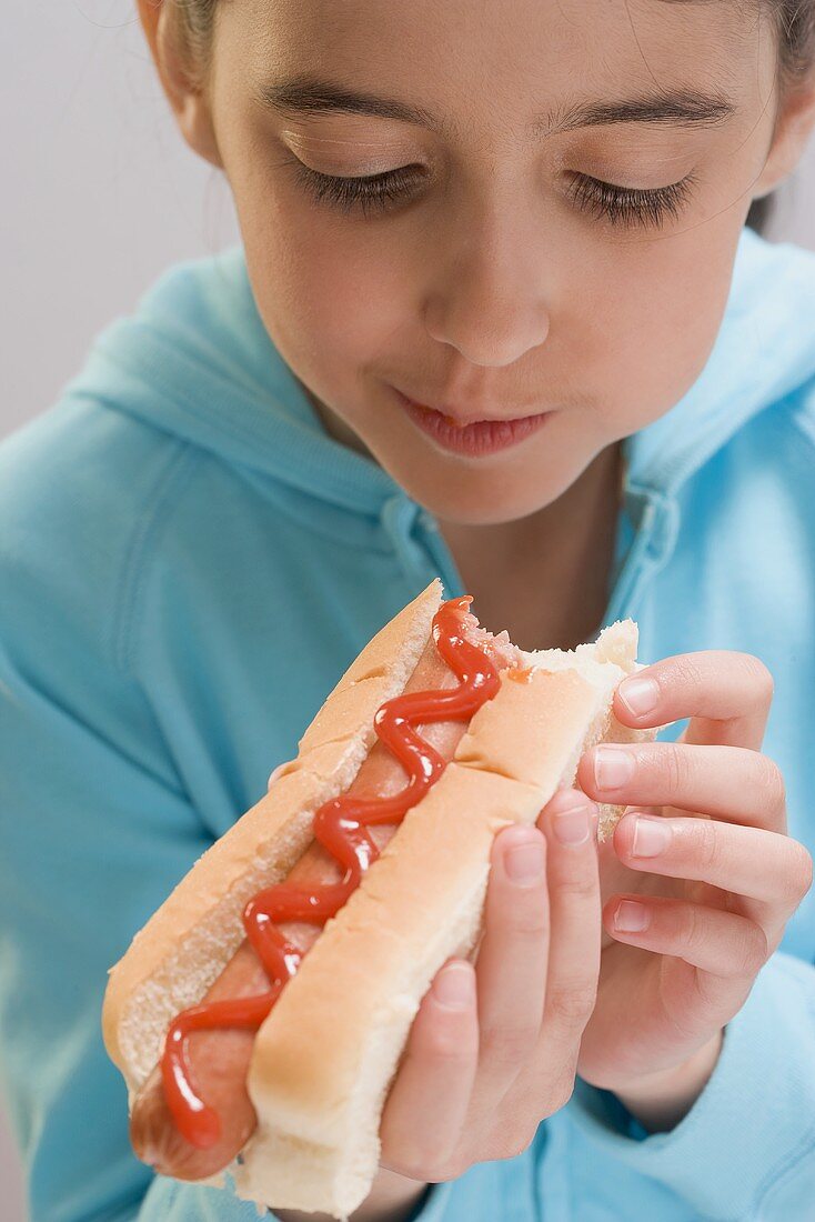Kleines Mädchen isst Hot Dog mit Ketchup
