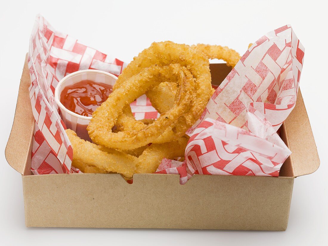 Deep-fried onion rings with ketchup in a cardboard box