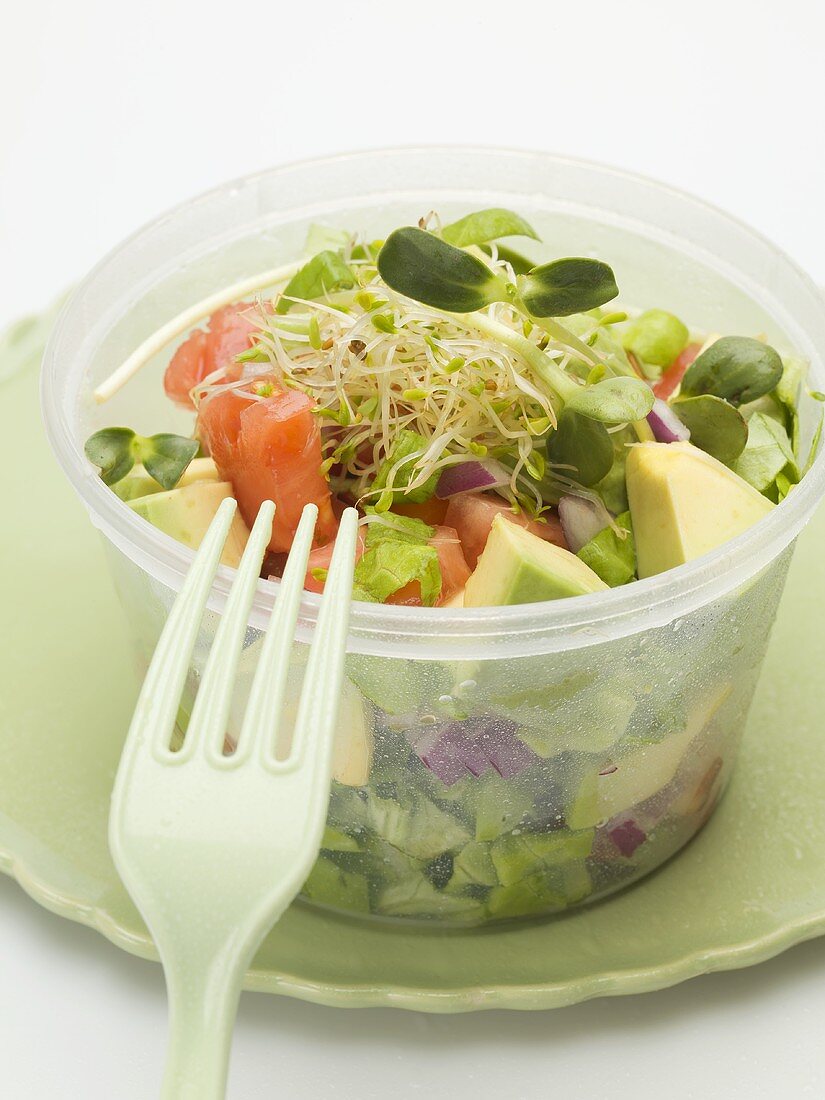 Avocadosalat mit Sprossen in Plastikschale mit Gabel