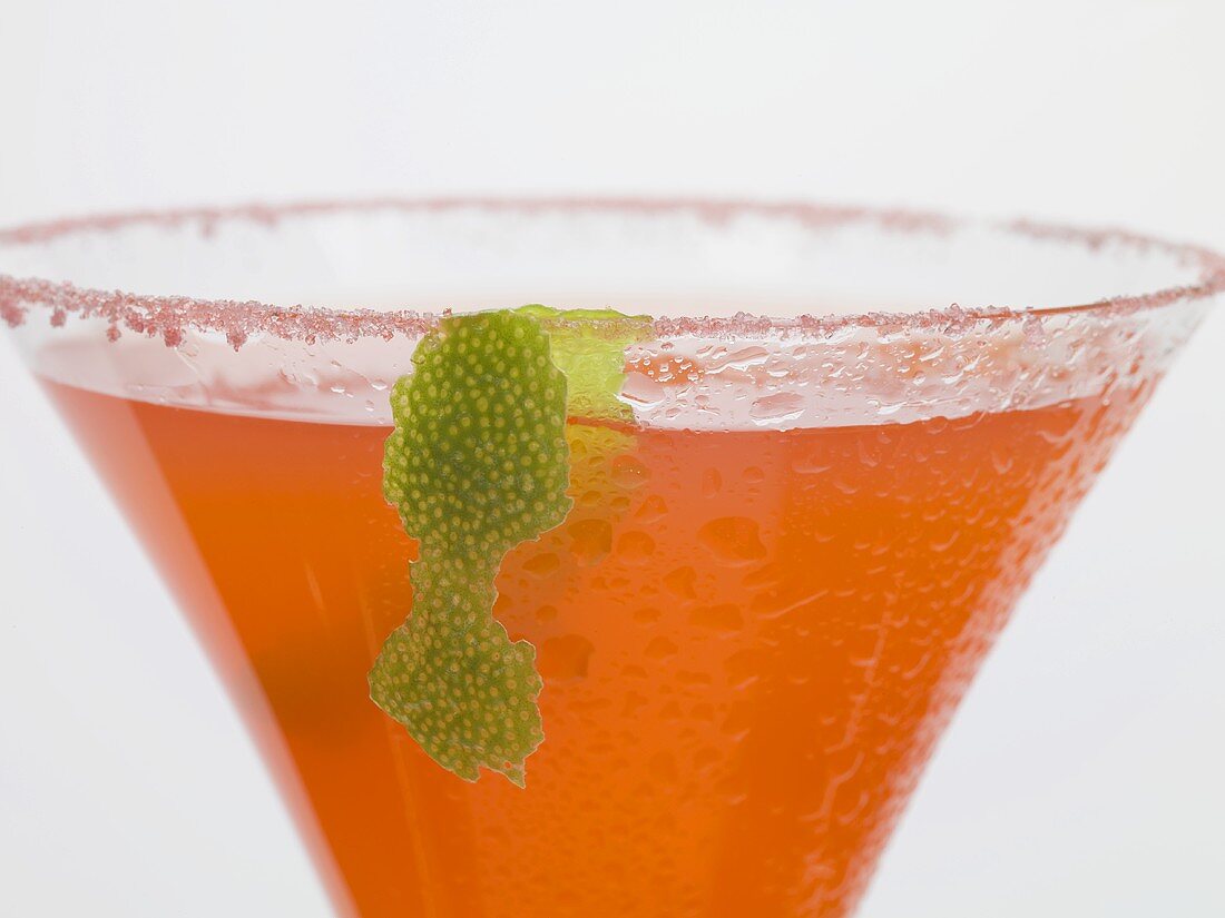Strawberry drink in glass with sugared rim and lime peel