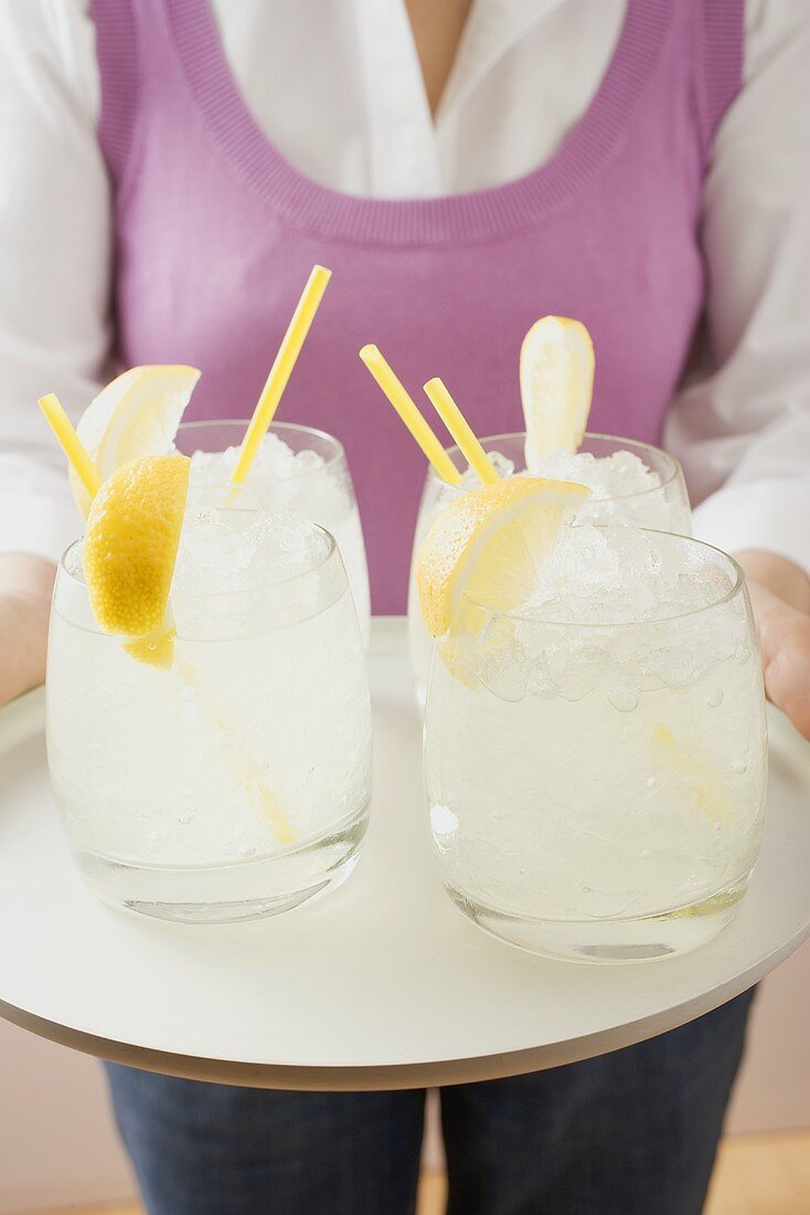 Woman holding tray of glasses filled with lemonade