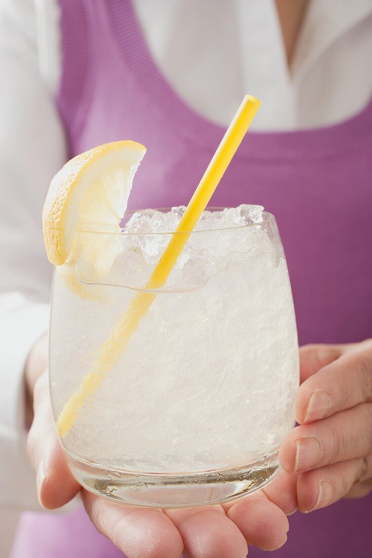 Woman holding glass of lemonade with straw