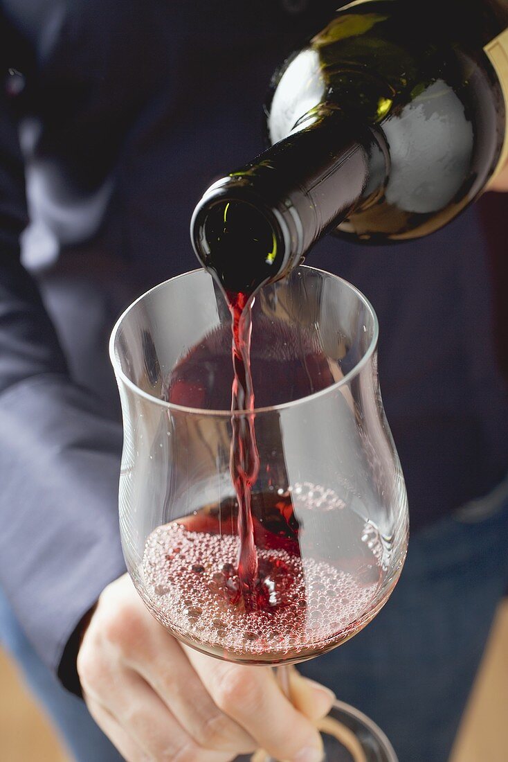 Woman pouring red wine into a glass