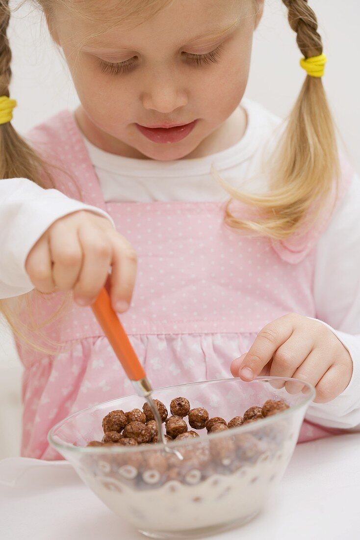 Little girl eating cereal with milk