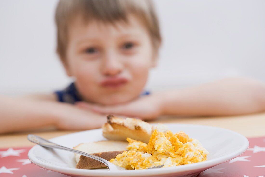 Scrambled egg with toast, little boy in background