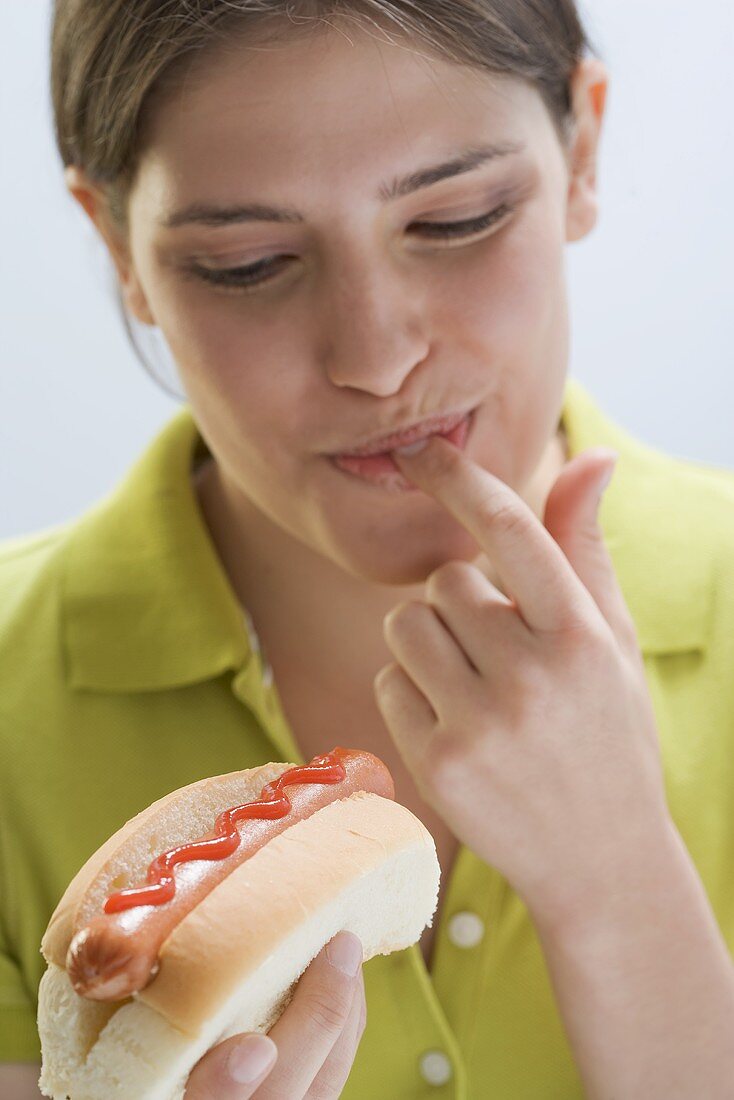 Junge Frau kostet Ketchup auf Hot Dog