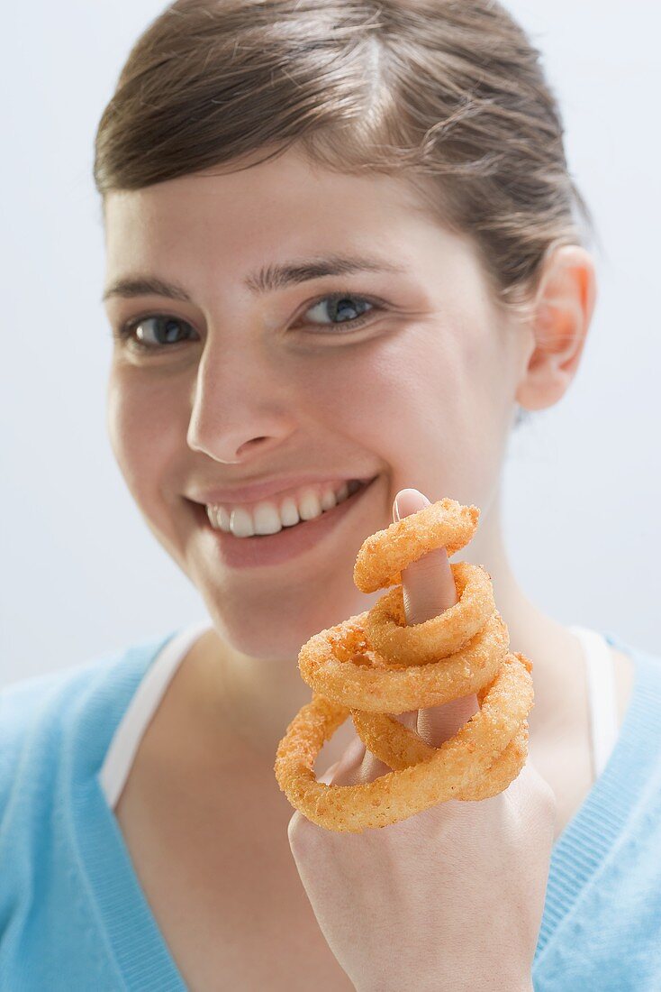 Young woman with deep-fried onion rings on index finger