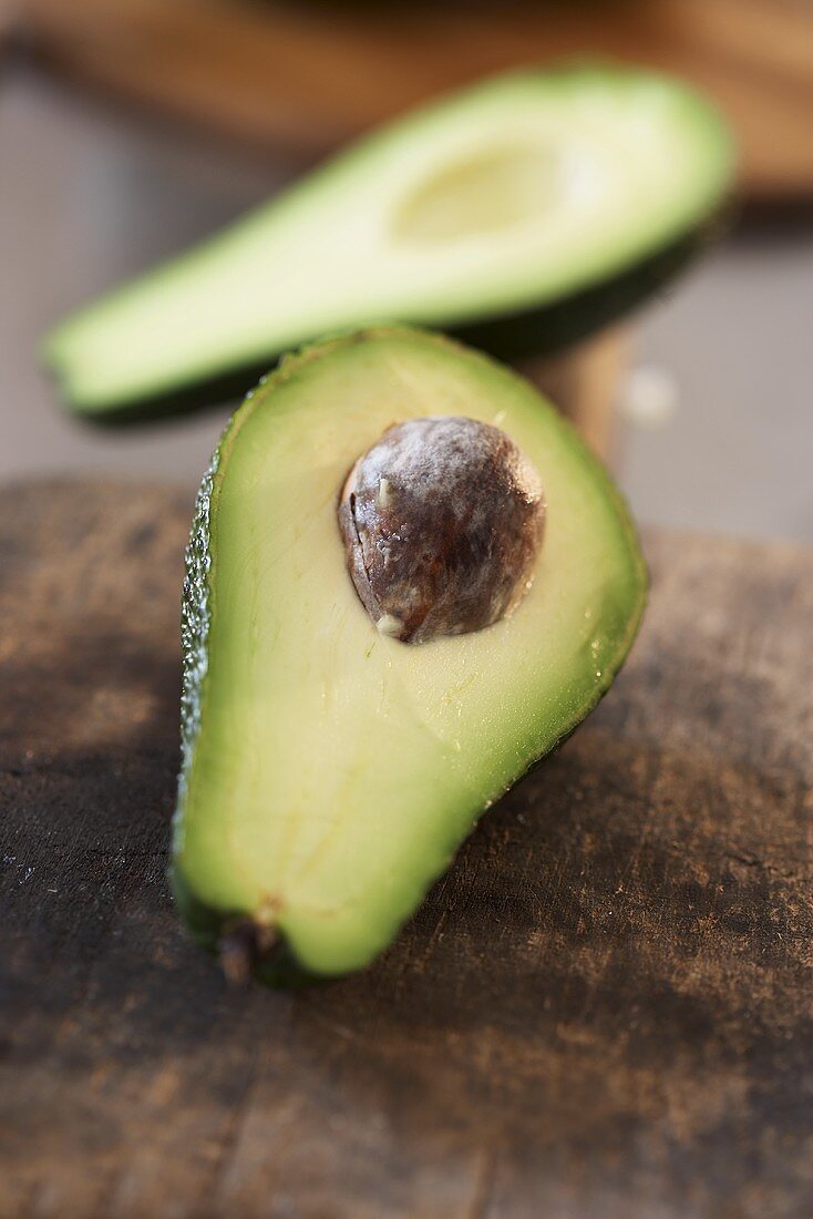 Avocado, halved, on old chopping board