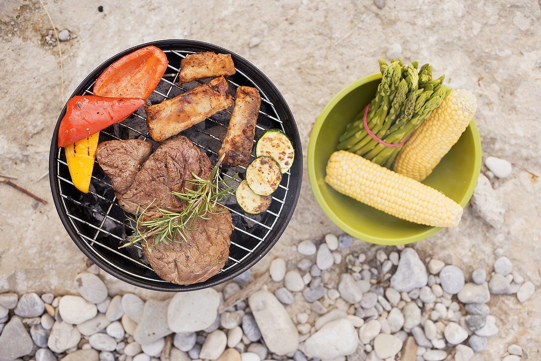 Gemüse und Fleisch auf Holzkohlengrill, Beilagen in Schüssel