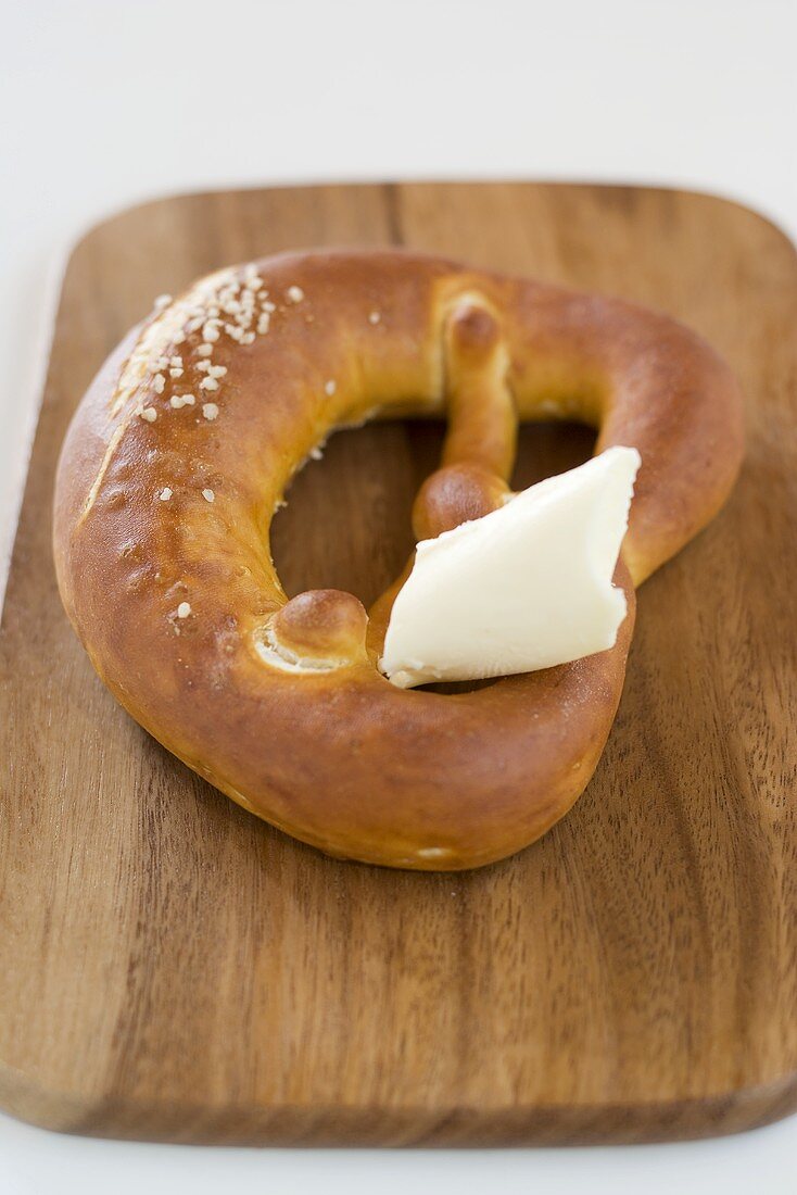 Pretzel with butter on chopping board