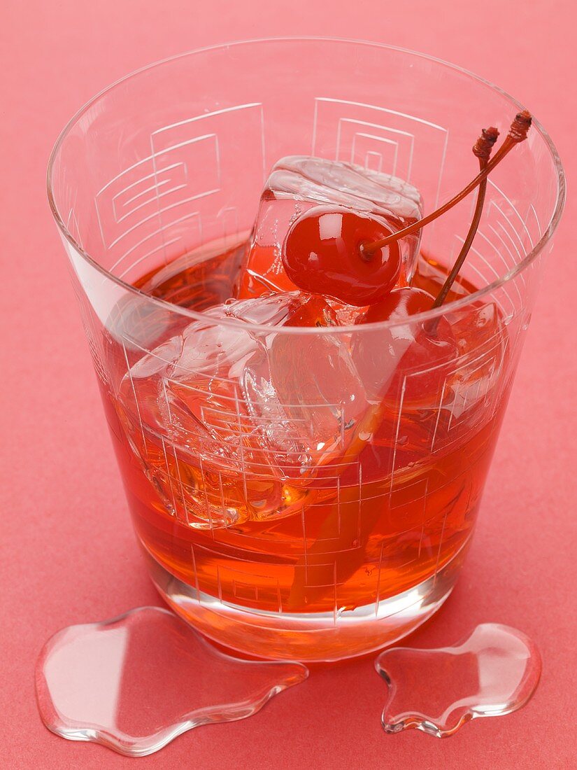 Manhattan with cocktail cherries and ice cubes