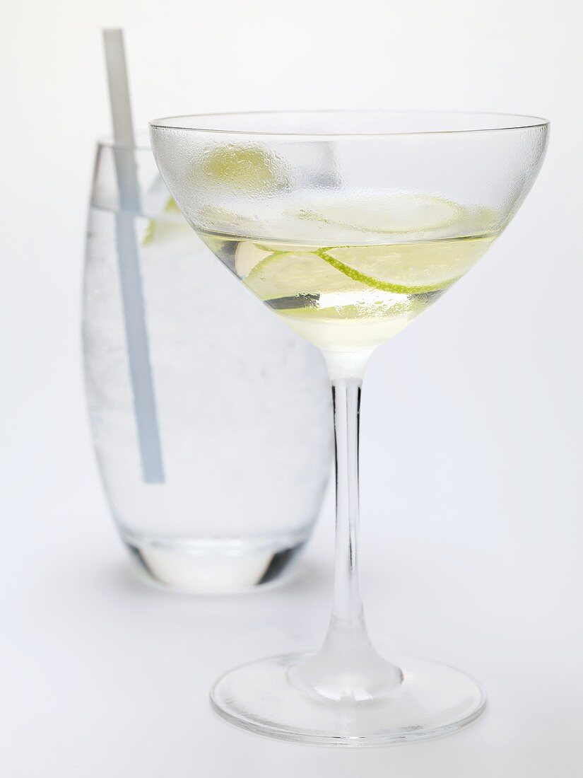 Drink mit Limettenscheiben, im Hintergrund Glas Wasser