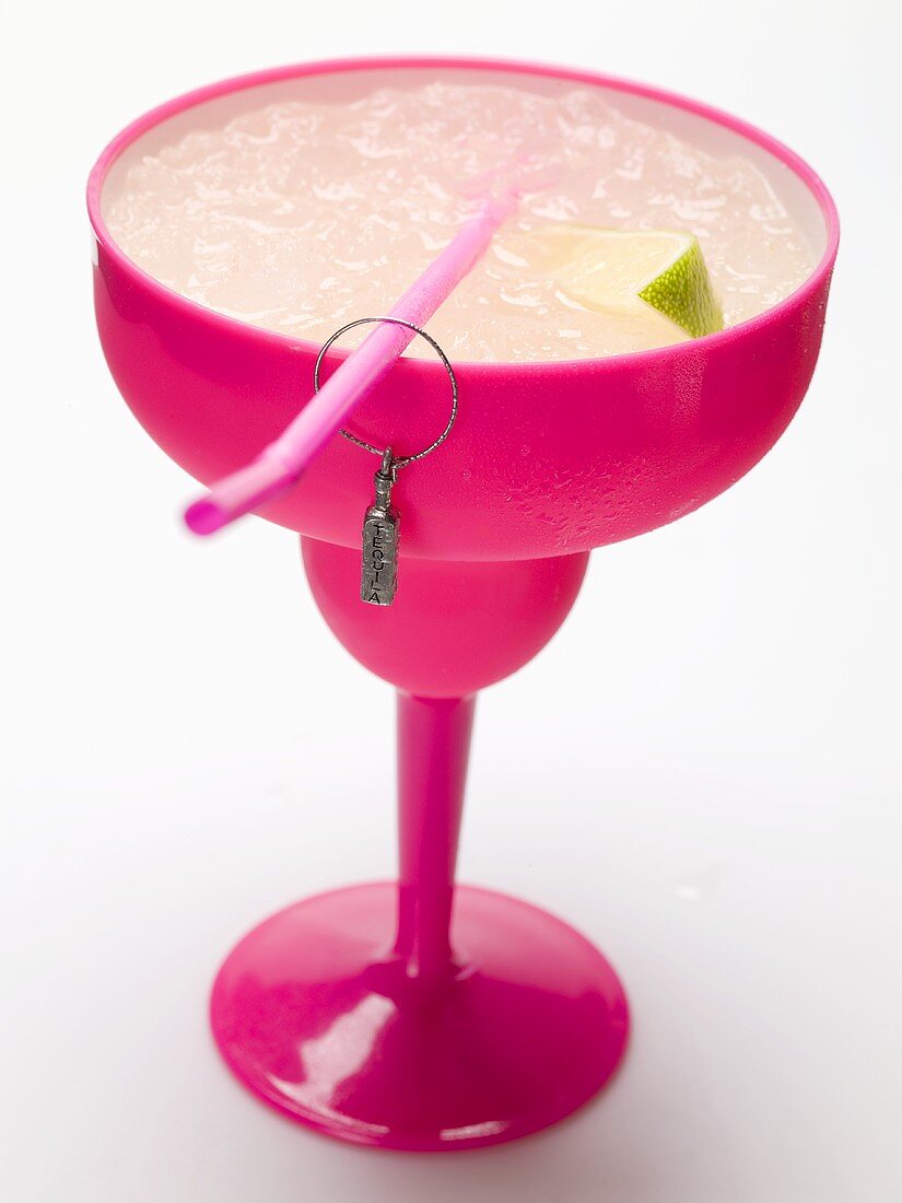 Frozen Margarita with lime wedges in pink glass