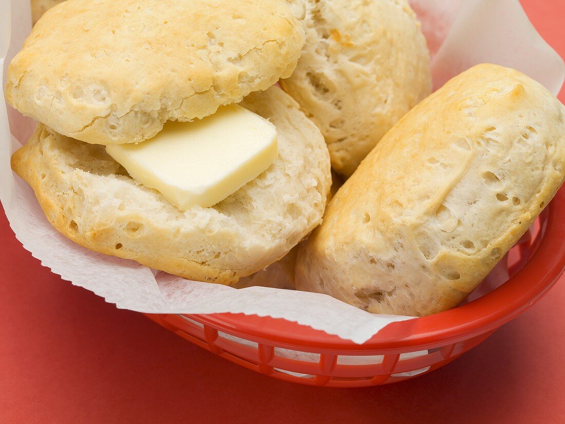 Scones in a plastic basket (one with butter)