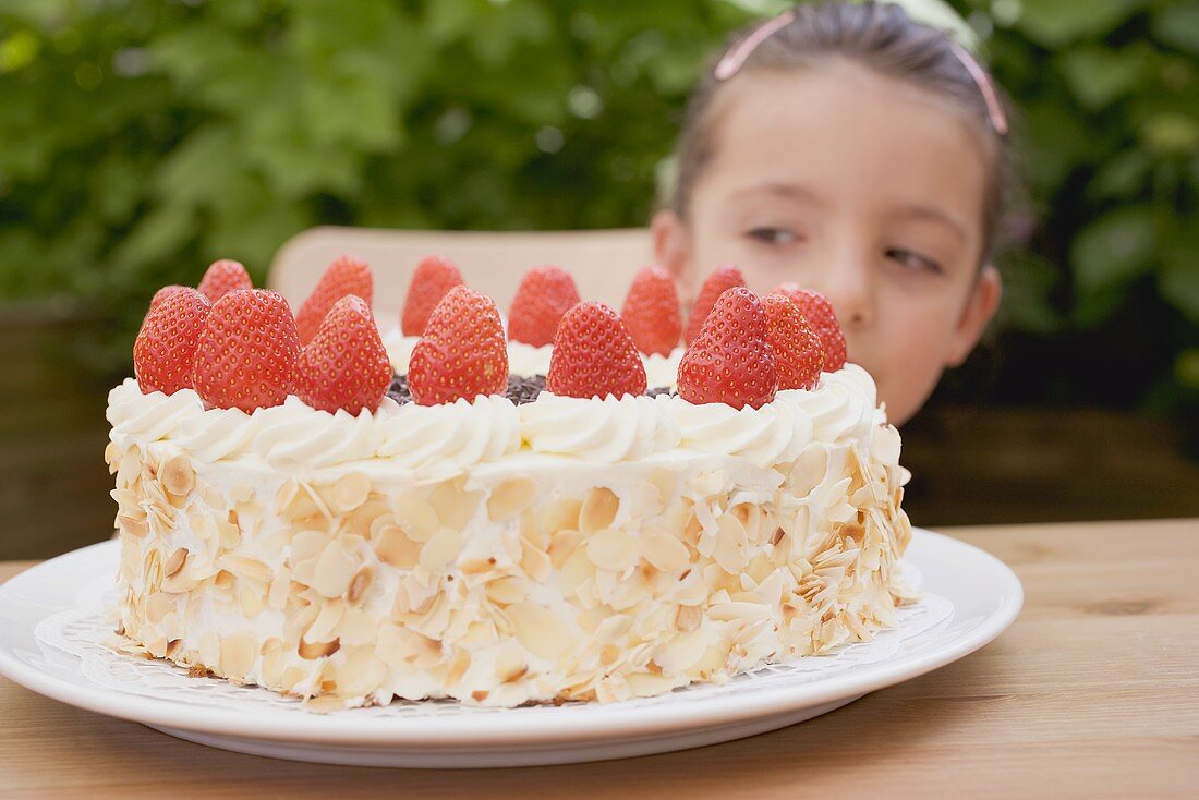 Little girl behind a large strawberry gateau