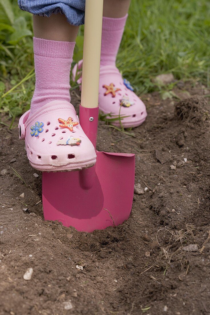 Kleines Mädchen sticht mit Schaufel in die Erde