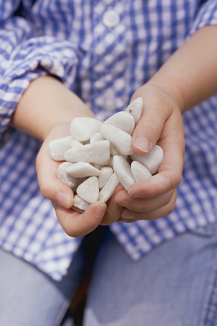 Kind hält eine Handvoll Kieselsteine