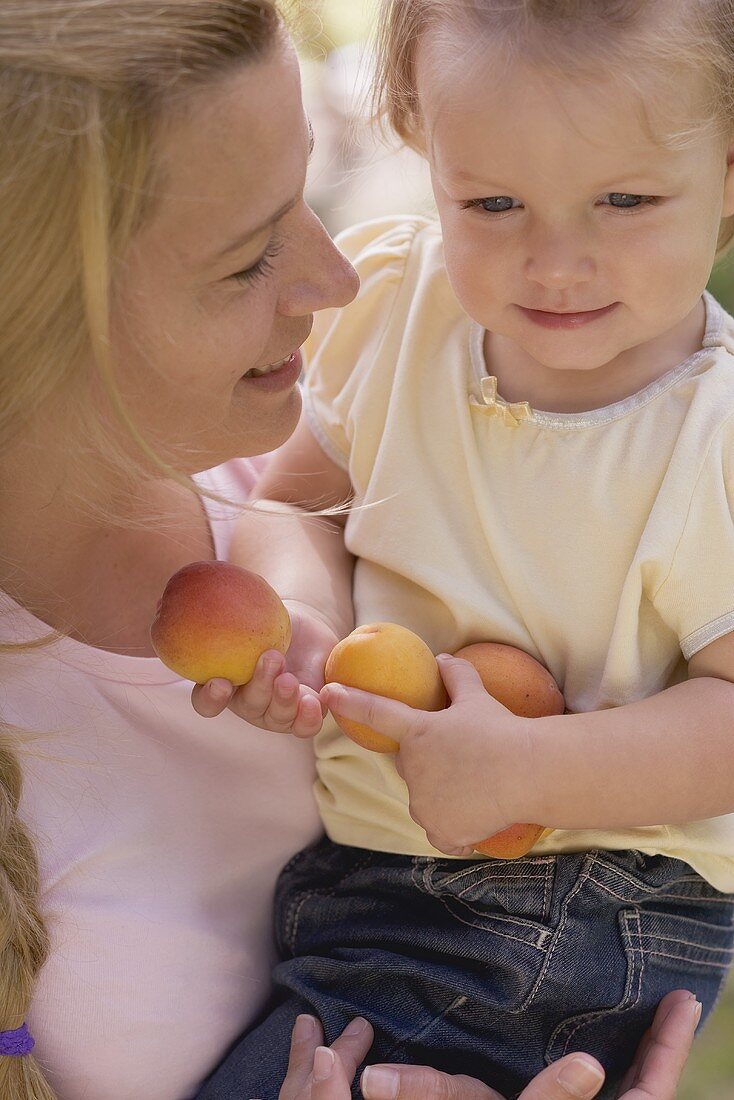 Mutter und kleine Tochter mit Aprikosen