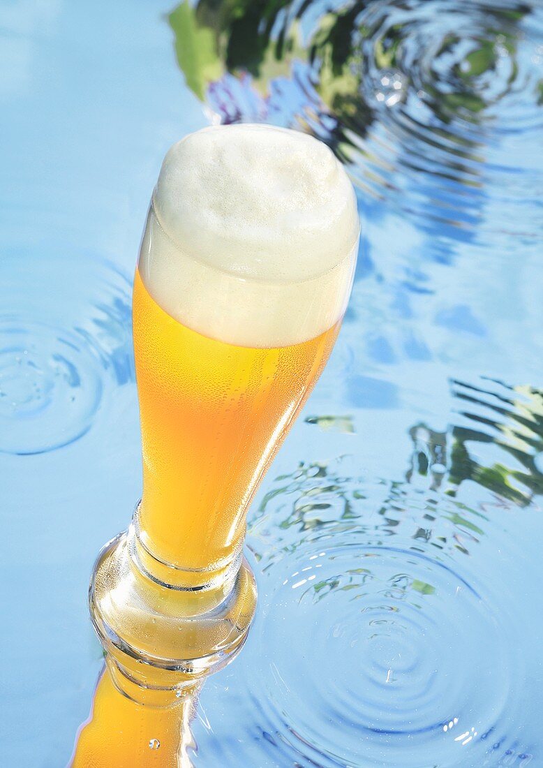 Glas Weissbier auf Wasserfläche