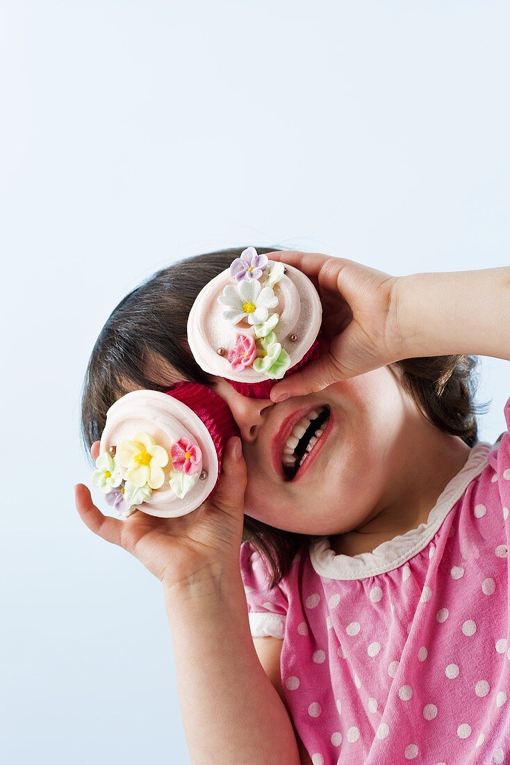 Girl with two cupcakes in front of her eyes