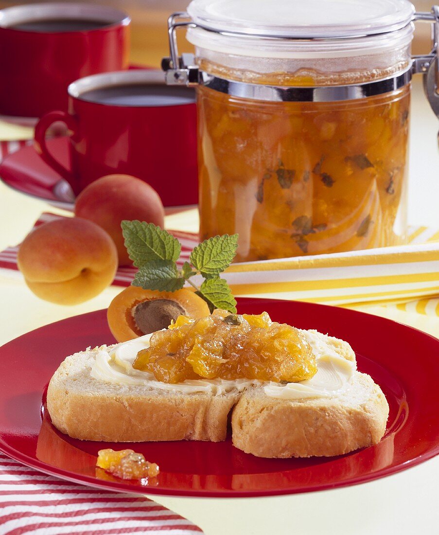 Aprikosen-Nektarinenkonfitüre im Einmachglas und Brotscheibe