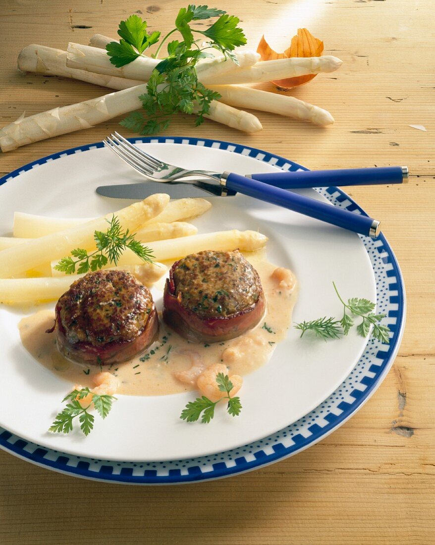 Bacon-wrapped meat patties with shrimp sauce and asparagus