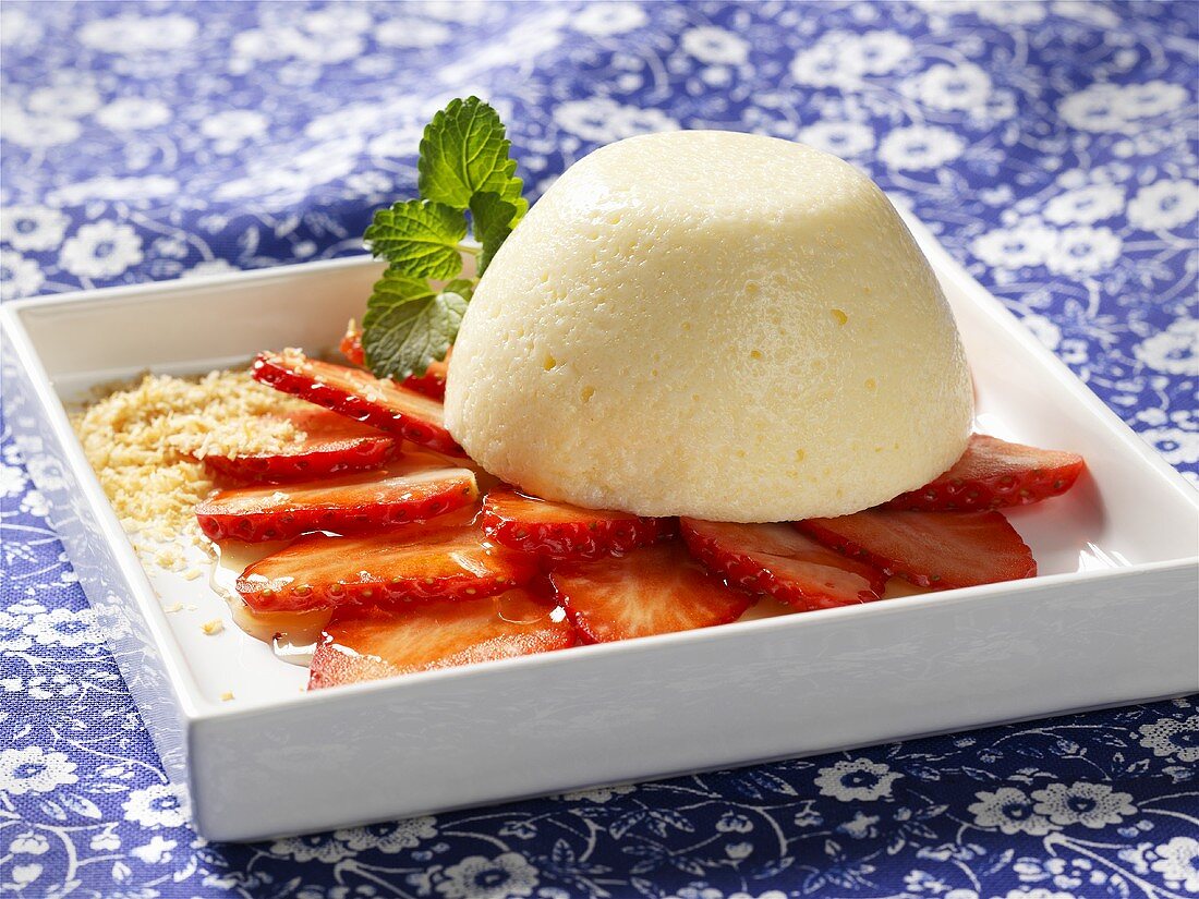 Moulded coconut and semolina pudding on strawberries