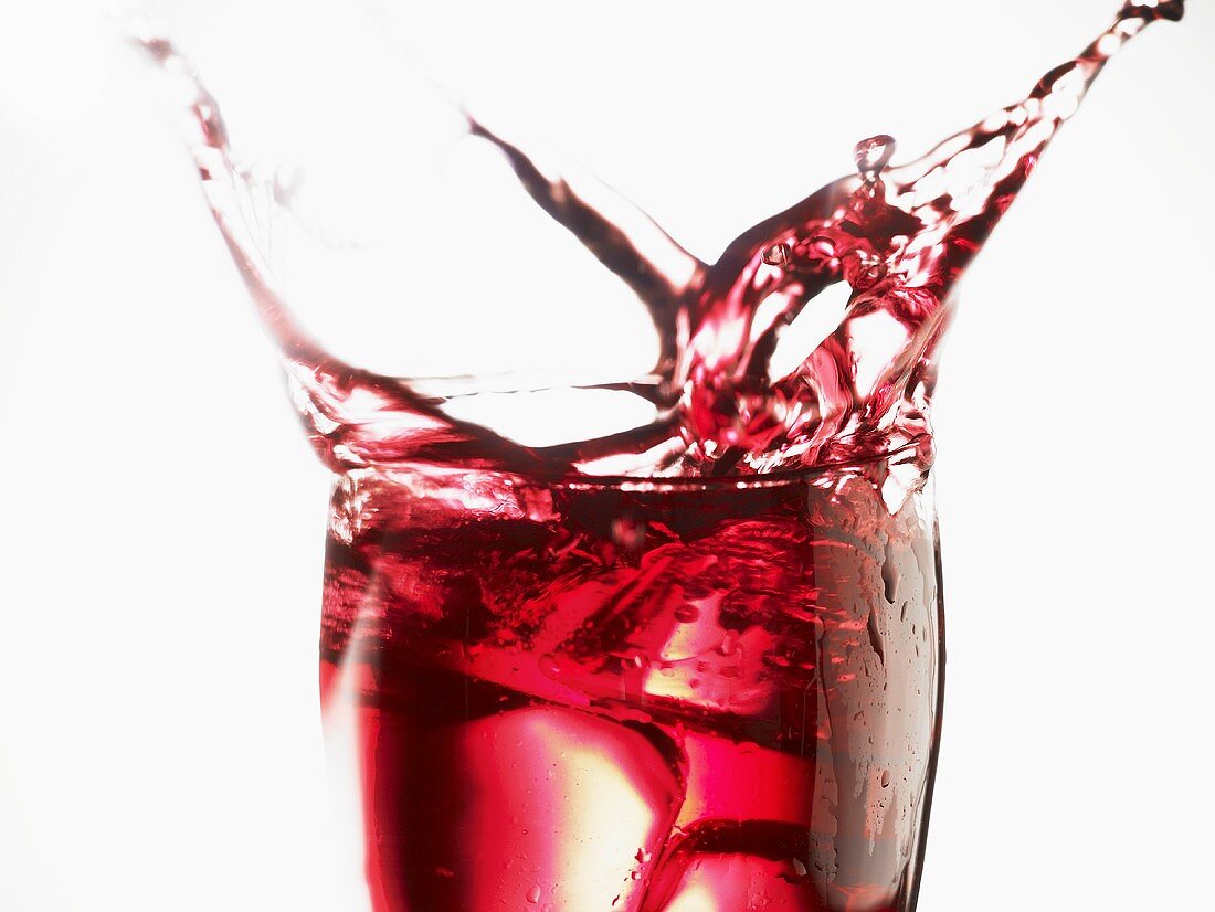 Cranberry juice splashing out of a glass