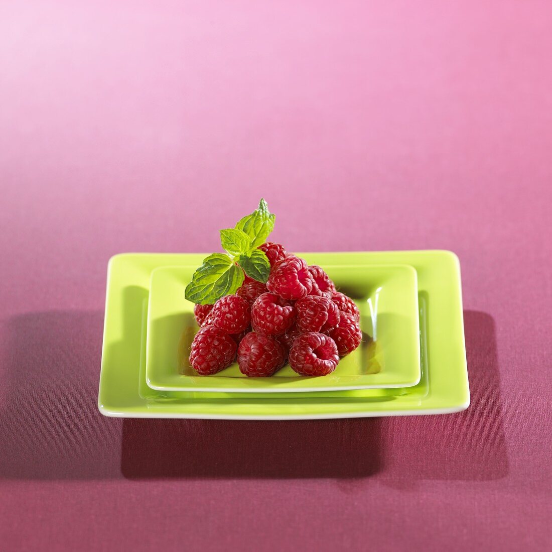 Fresh raspberries in square green dish