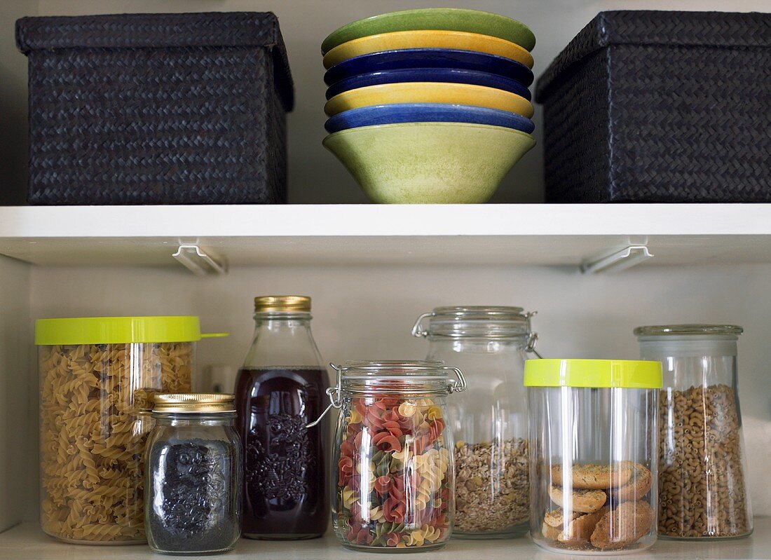 Preserving jars, dishes and baskets on kitchen shelves