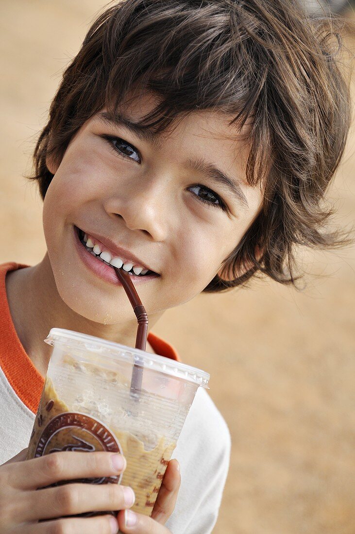 Lächelnder Junge trinkt Kakao mit Eis