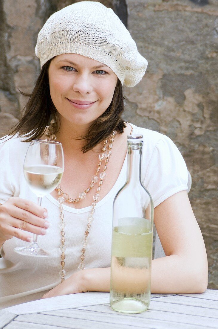 Young woman with glass of white wine and wine bottle