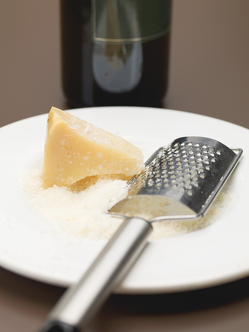 Parmesan, partly grated, with cheese grater on plate