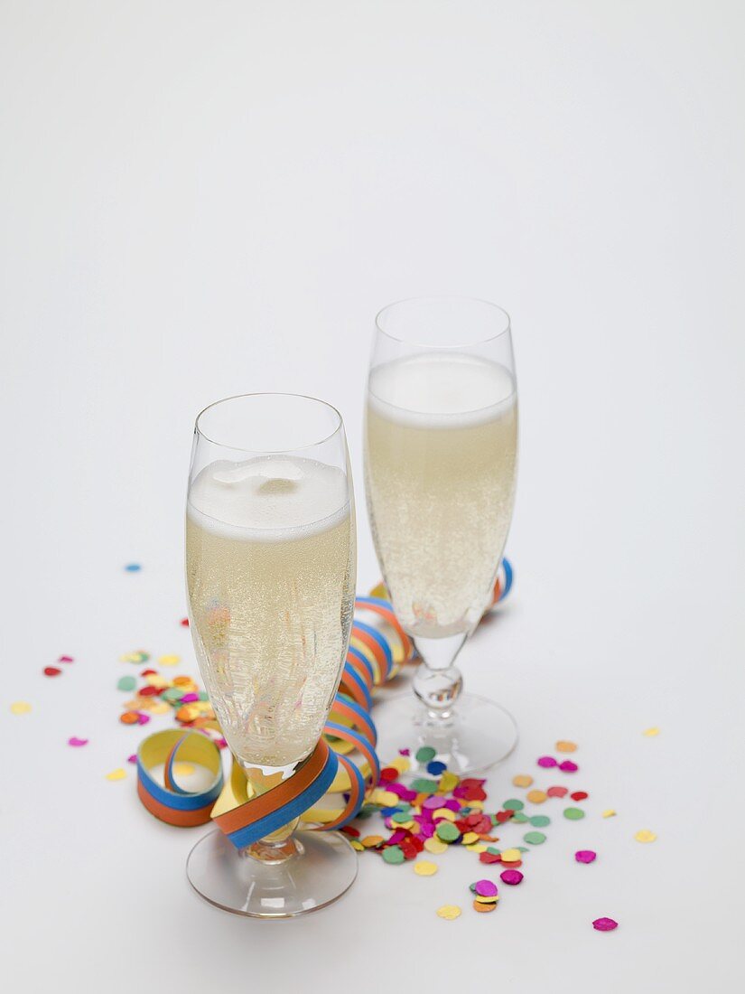 Two glasses of sparkling wine, paper streamer and confetti