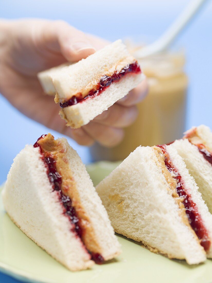 Hand hält Sandwich mit Erdnussbutter und Marmelade