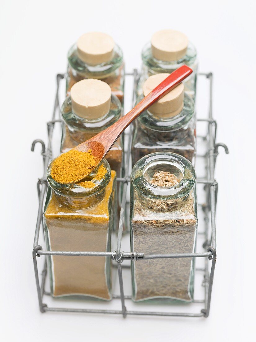 Various spices in small glass bottles and on spoon