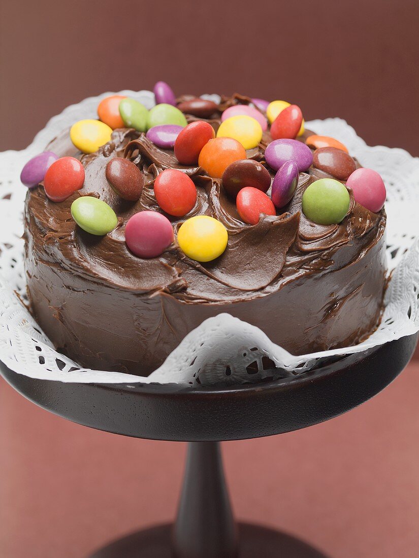 Schokoladentorte mit bunten Schokolinsen auf Kuchenständer