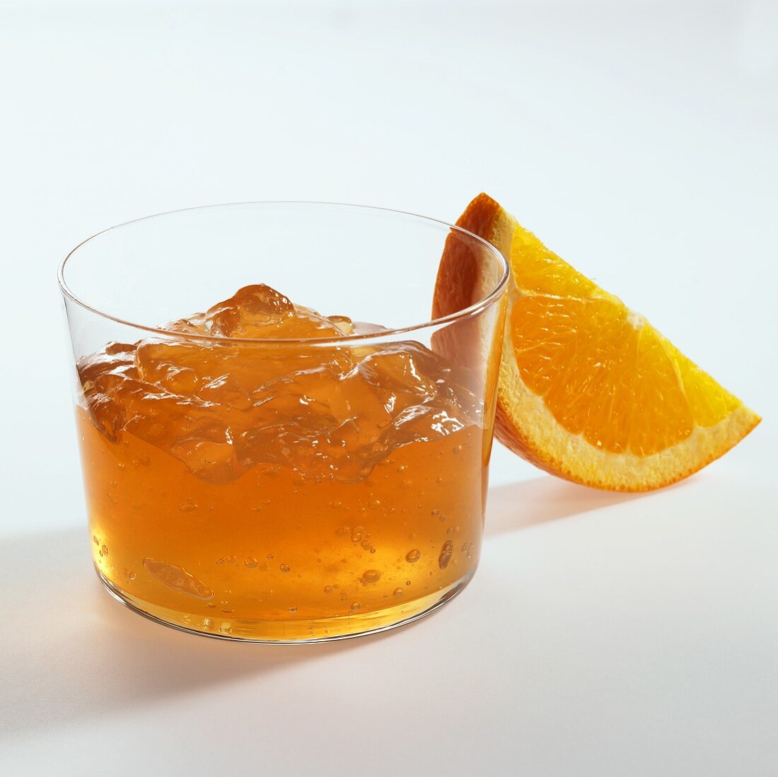 Orange jelly in glass, orange wedge beside it